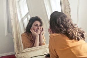 girl looking in the mirror smiling at herself