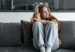 girl sitting on a couch looking sad